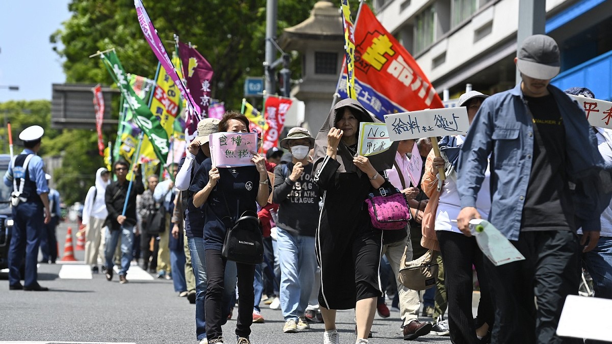 Ținând în mâini pancarte și scandând, oamenii mărșăluiesc de 1 Mai, în Japonia
