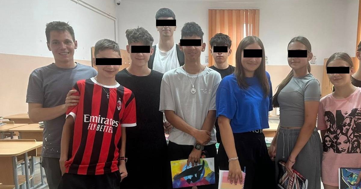 Studentul Raul Nemeș, alături de mai mulți elevi cărora le acordă meditații gratuite la matematică, stau cu toții în picioare la o poză de grup, în sala de clasă