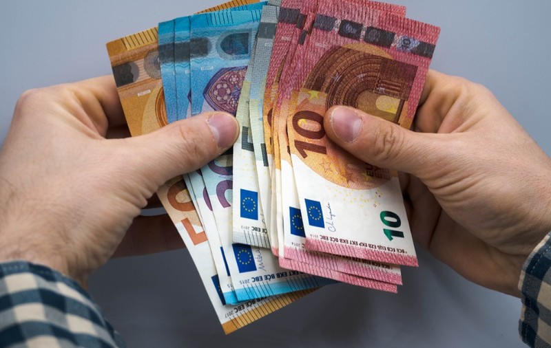 Un bărbat care ține mai multe bancnote de euro 