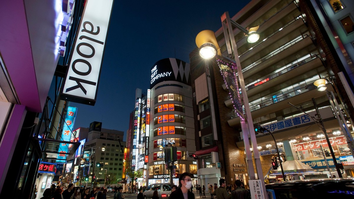Firmele cu neon lumineaza clădirile comerciale din cartierul aglomerat de cumpărături și divertisment din East Shinjuku, în centrul orașului Tokyo, Japonia.