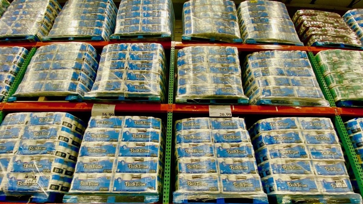 Baxuri de hârtie igienică așezați pe paleți, iar paleții stivuiți pe rafturi într-un depozit