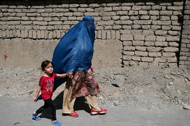 O femeie îmbrăcată cu burka merge pe o stradă din Kabul, alături de o fetiță | Foto: Profimedia