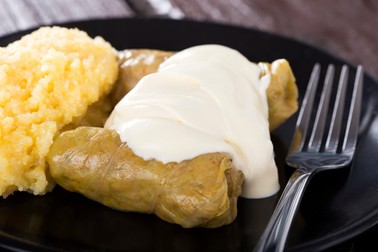 Cabbage rolls filled with minced meat and rice on plate with polenta, over wooden table