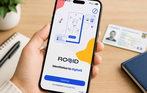 O mână ține un smartphone pe ecranul căruia este deschisă aplicația ROeID, cu mesajul „Identitatea ta digitală”. Pe masă, în fundal, se află o carte de identitate românească.