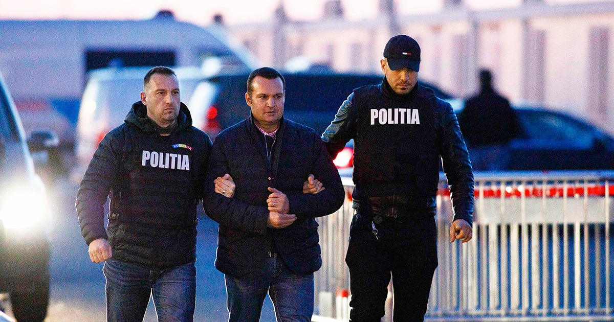 Cătălin Cherecheș cu cătușe la mâini și încadrat de doi polițiști.