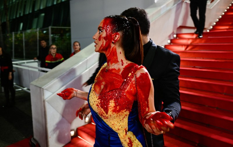 Protest pe covorul roșu de la Cannes. O femeie îmbrăcată în culorile steagului ucrainean s-a stropit cu vopsea roșie