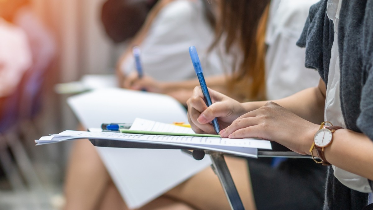 Mai multi elevi care stau în bănci, la scoala, si dau un examen scris.