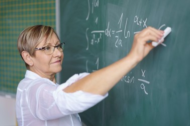 Profesoară în vârstă care scrie la tablă