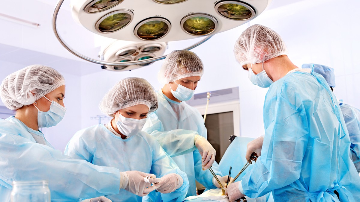 Mai mulți medici operează un pacient, într-o sală de operații
