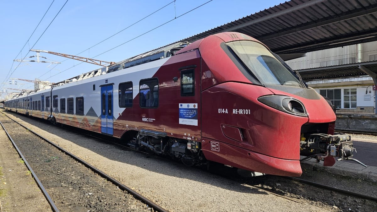 Imaginea prezintă un tren modern Alstom Coradia Stream, aflat în stație, cu un design aerodinamic și culori roșu-alb. Garnitura sugerează modernizarea transportului feroviar și introducerea unor condiții mai confortabile pentru călători.