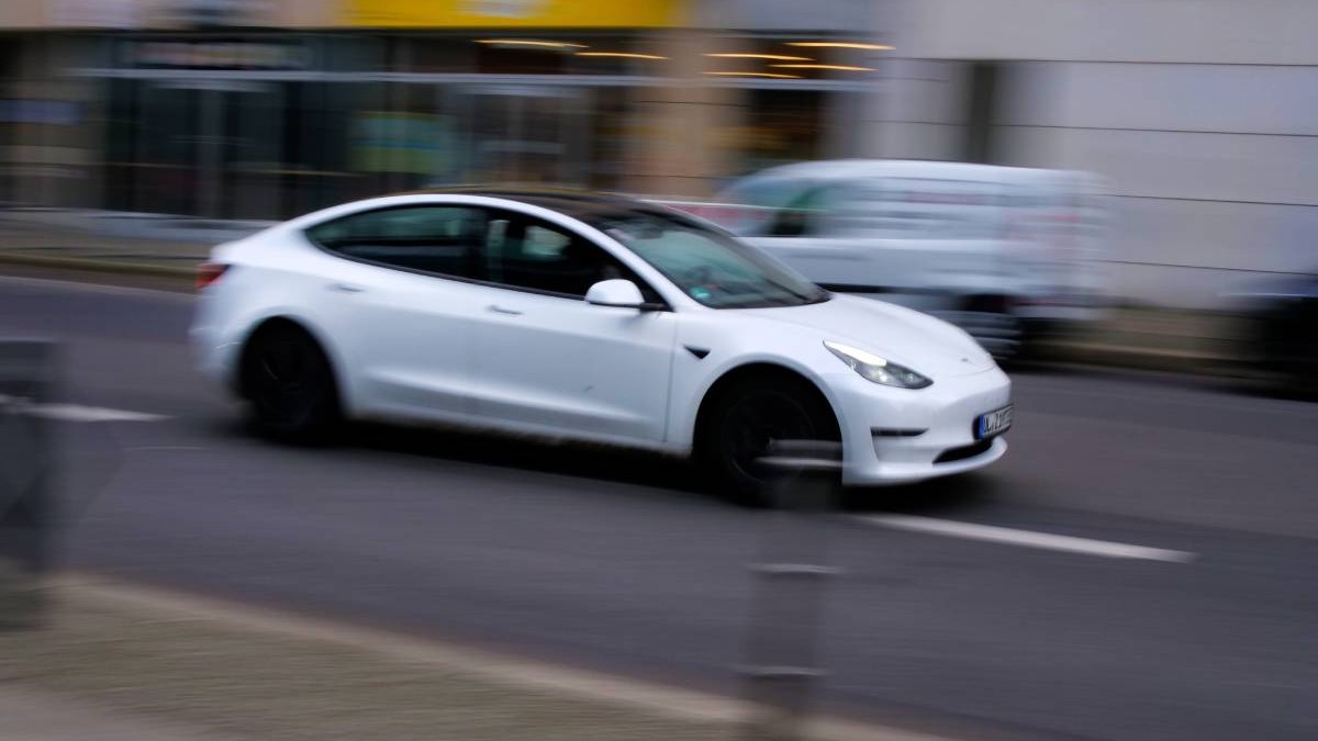 Mașină electrică Tesla Model 3 albă în mers pe o stradă în oraș
