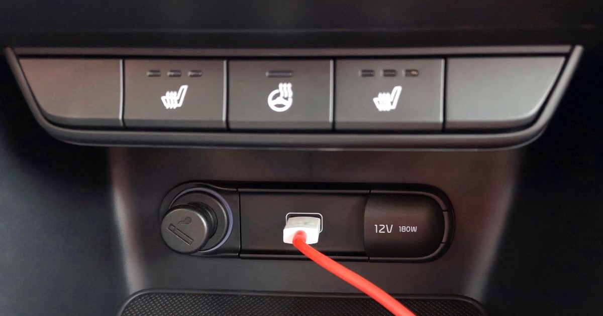 Bordul negru al unei mașini, cu un cablu roșu care este conectat la o priză USB