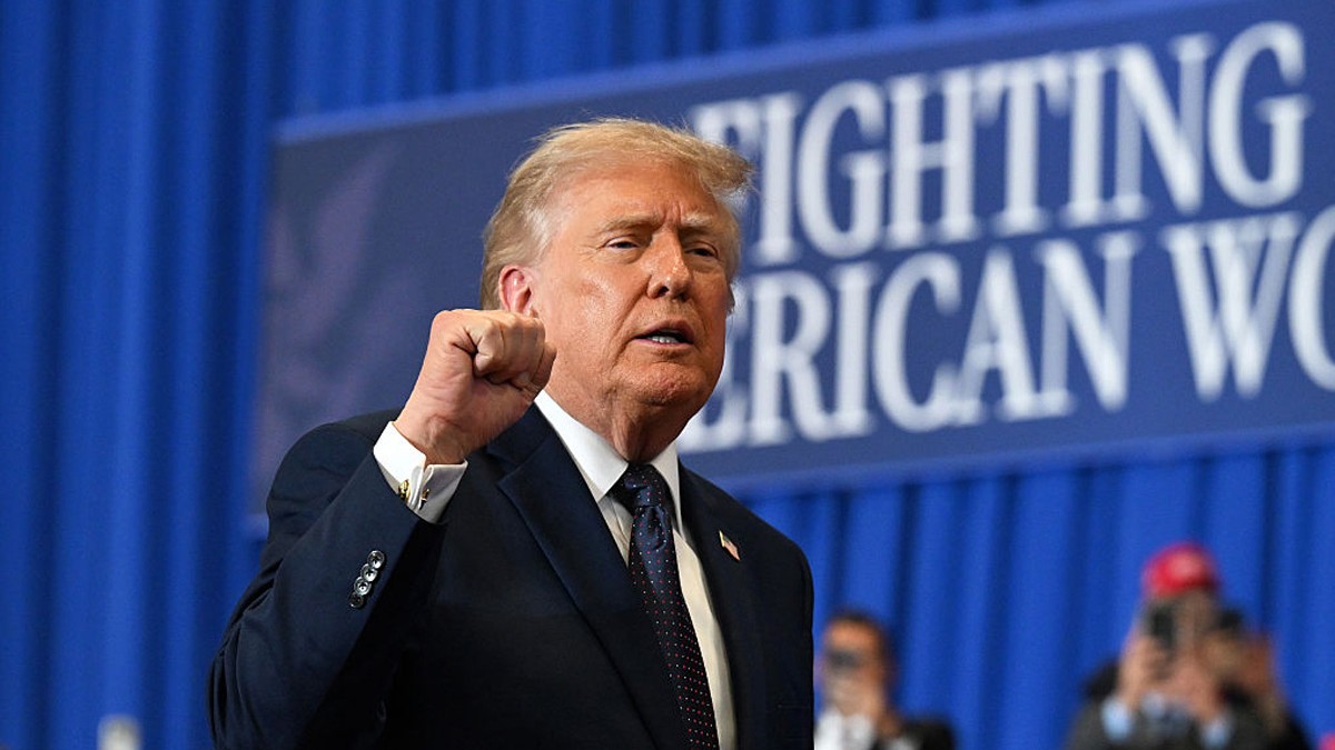Donald Trump, îmbărcat în sacou negru, cămașă albă și cu cravată bleumarin, ridică pumnul drept în sus în semn de a transmite putere la un eveniment „Fight America” Foto: Getty Images