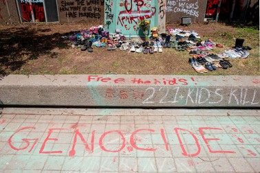 215 pantofi depuși în fața statuii lui Egerton Ryerson din campusul Universității Ryerson, vandalizat cu vopsea din care s-a scris „Genocid” după descoperirea celor 215 cadavre ale copiilor din școala rezidențială din Kamloops, British Columbia. Egerton Ryerson a fost primul arhitect al sistemului rezidențial de școli. | Foto: EPA
