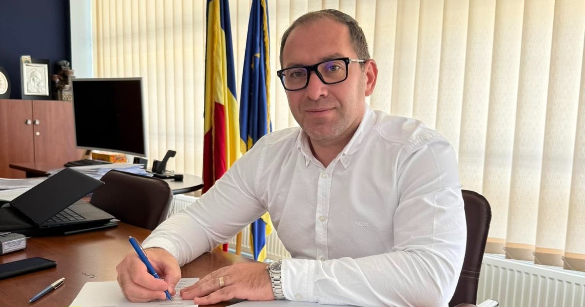 Marian Bârgău, la birou la Administrația Străzilor București, în timp ce poartă o cămașă albă și semnează un document