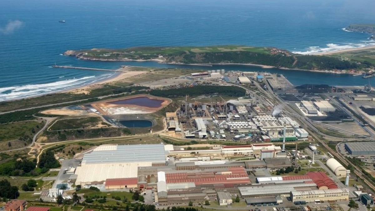 Imagine aeriană a fabricii Saint-Gobain din Avilés, în nordul Spaniei, unde urmează să fie construit cuptorul hibrid pentru sticlă estimat la 120 de milioane de euro. Complexul industrial se întinde pe o suprafață mare, chiar lângă coastă, între hale de producție, linii industriale și bazine, cu Oceanul Atlantic în fundal. Aici va fi instalat noul cuptor care va combina electricitatea și gazul și va topi sticla la temperaturi de până la 1.600°C.