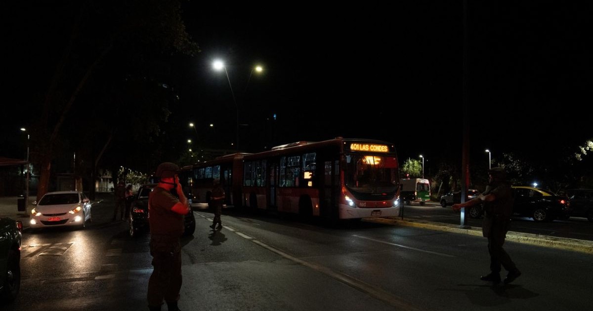 Este pană masivă de curent în Chile, două autobuze se văd pe stradă, câteva mașini și un polițist, în întuneric