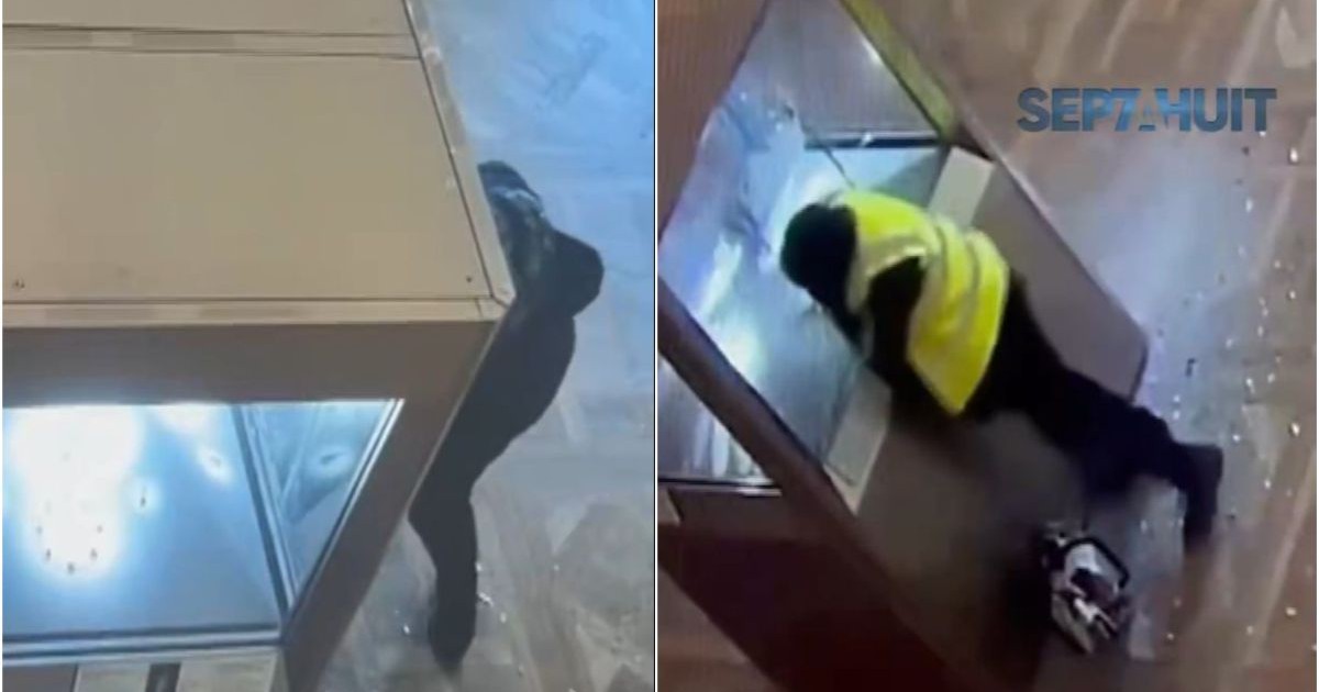 În stânga, un bărbat îmbrăcat în negru se vede lângă o cabină albă, iar în dreapta, un alt bărbat care are o vestă galbenă bagă mâna în vitrină și sprage un geam pentru a fura bijuterii, în timpul jafului de la Muzeul Luvru din Franța, 19 octombrie 2025