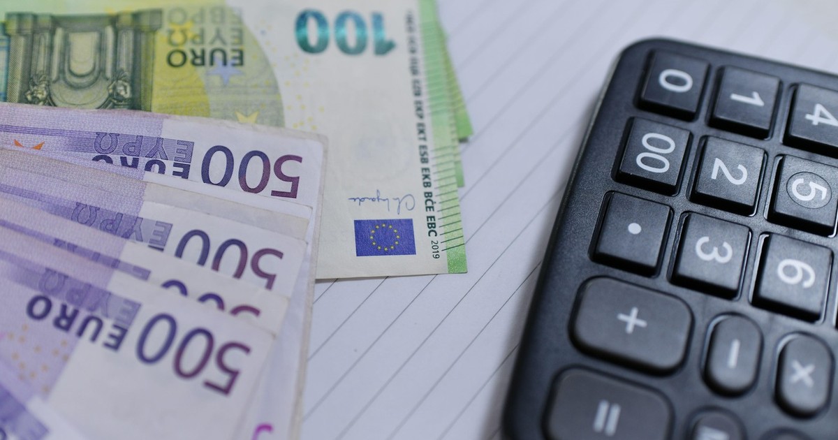 Bancnote de 500 și 100 de euro așezate în evantai, alături de un calculator