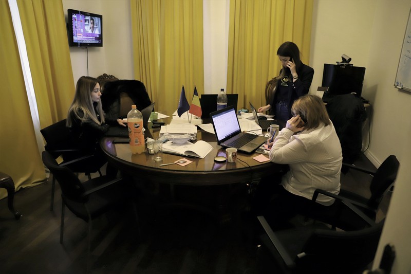 Membri ai AUR urmăresc cum se desfășoară scrutinul. Masca de protecție este aruncată pe masă, abia se observă printre toate foile