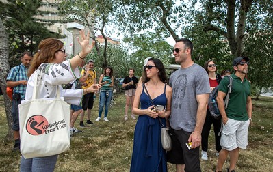 Oamenii o ascultă cu zâmbetul pe buze pe Cătălina, care le explică diverse lucruri despre Teatrul Național și despre statuia lui I.L. Caragiale din Piața Universității