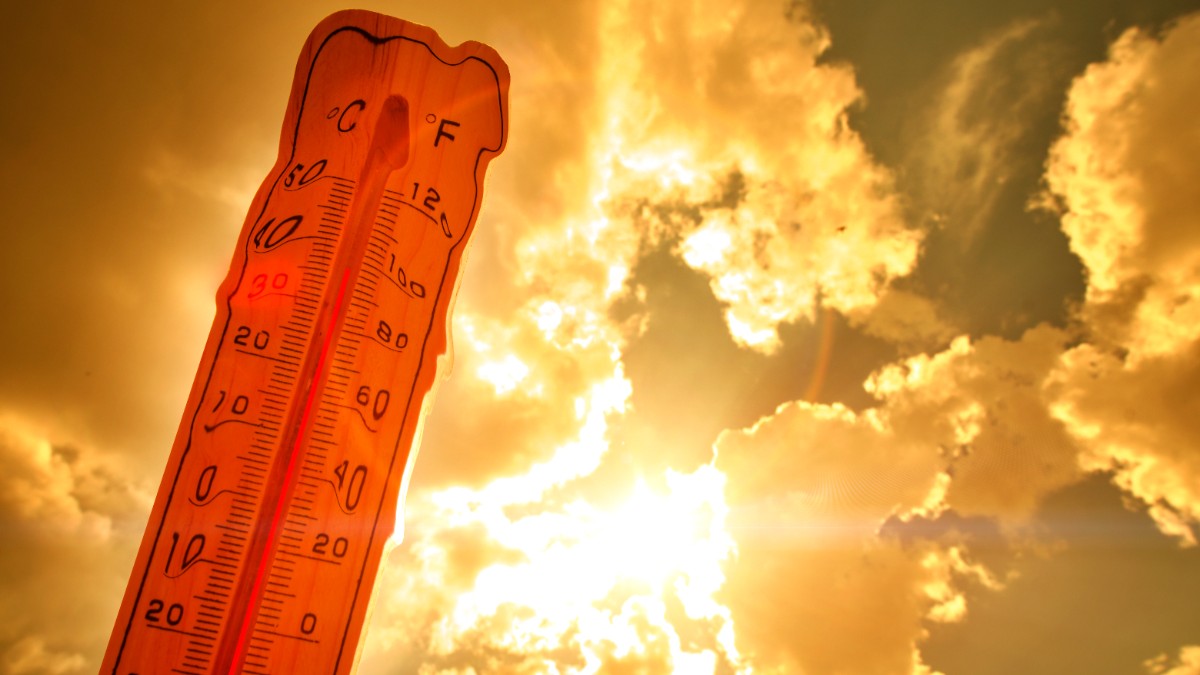 Imaginea prezintă un termometru din lemn profilat pe fundalul unui cer cald, portocaliu și strălucitor, indicând o temperatură ridicată de aproape 40°C.