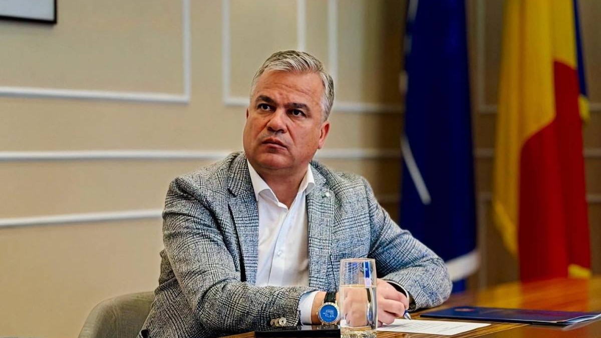 Adrian Veștea într-un costum gri, la un birou