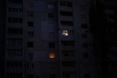 Un bărbat se uită pe fereastra apartamentului său, aflat într-un bloc avariat de explozii, în Kiev. Foto: Profimedia
