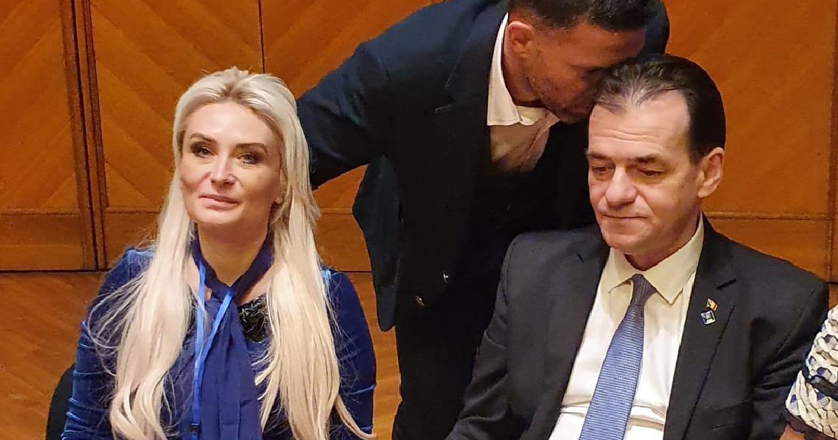 Avocata Adriana Georgescu în poză cu Ludovic Orban, în timp ce un bărbat îi șoptește ceva la ureche acestuia