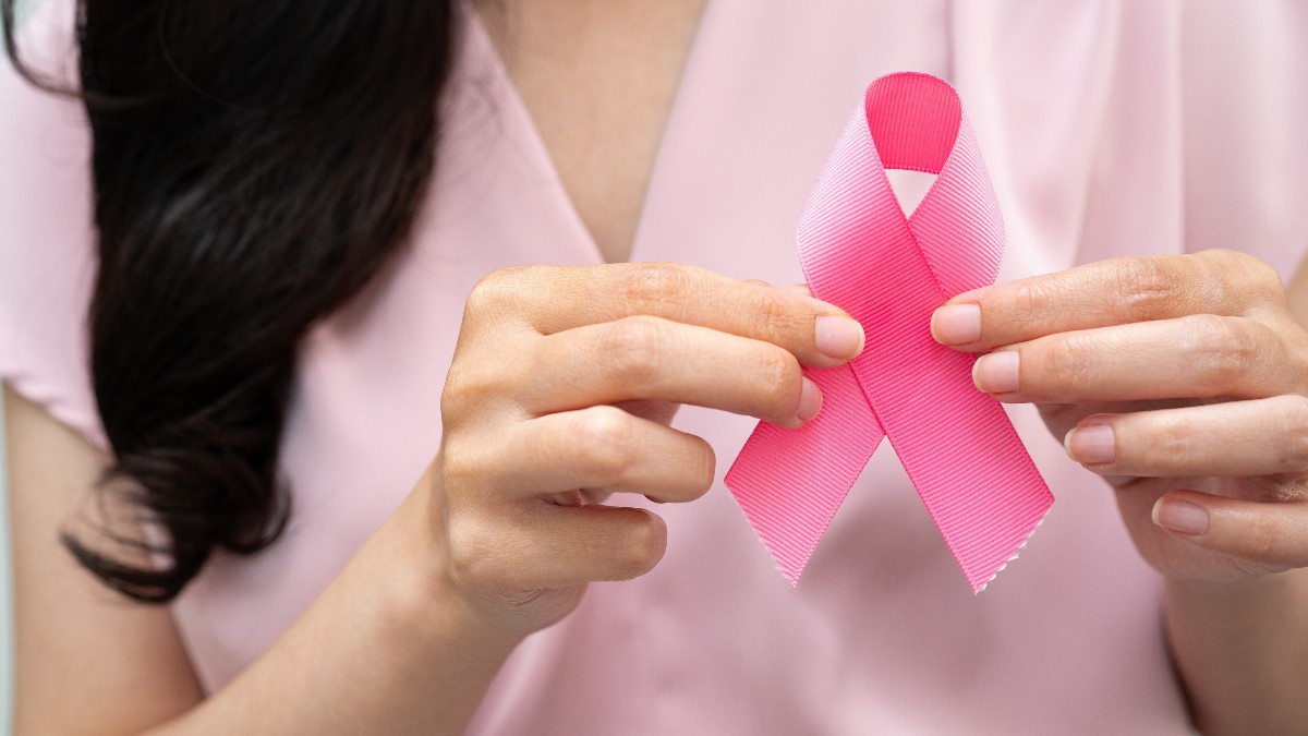 Imaginea prezintă o femeie care ține în mâini panglica roz, simbol internațional al luptei împotriva cancerului de sân. Fotografia transmite un mesaj de solidaritate, prevenție și susținere pentru persoanele afectate de această boală.