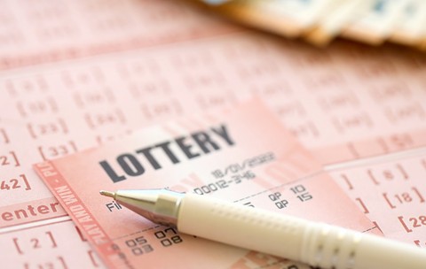 Un pix pe un bilet la loto. În fundal se văd mai multe bancnote 