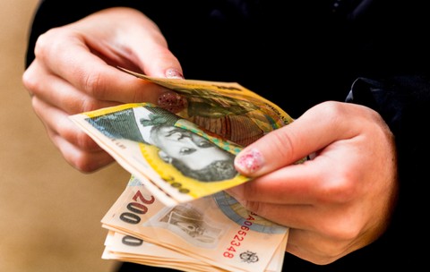 O tânără care numără mai multe bancnote de 200 de lei 