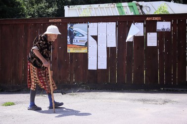 O femeie în vârstă se îndreaptă în baston spre cabinetul medicului de familie