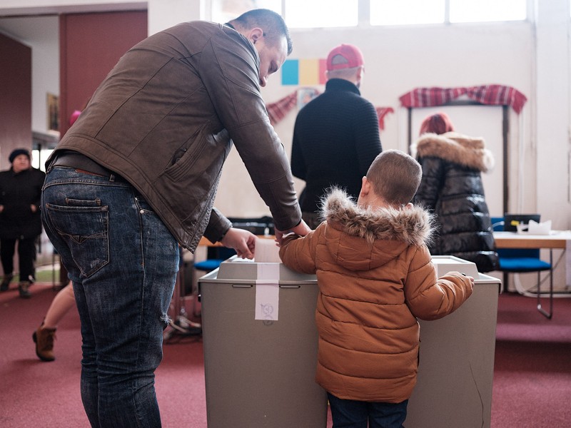 Un tată îi arată fiului cum să introducă buletinul în urnă