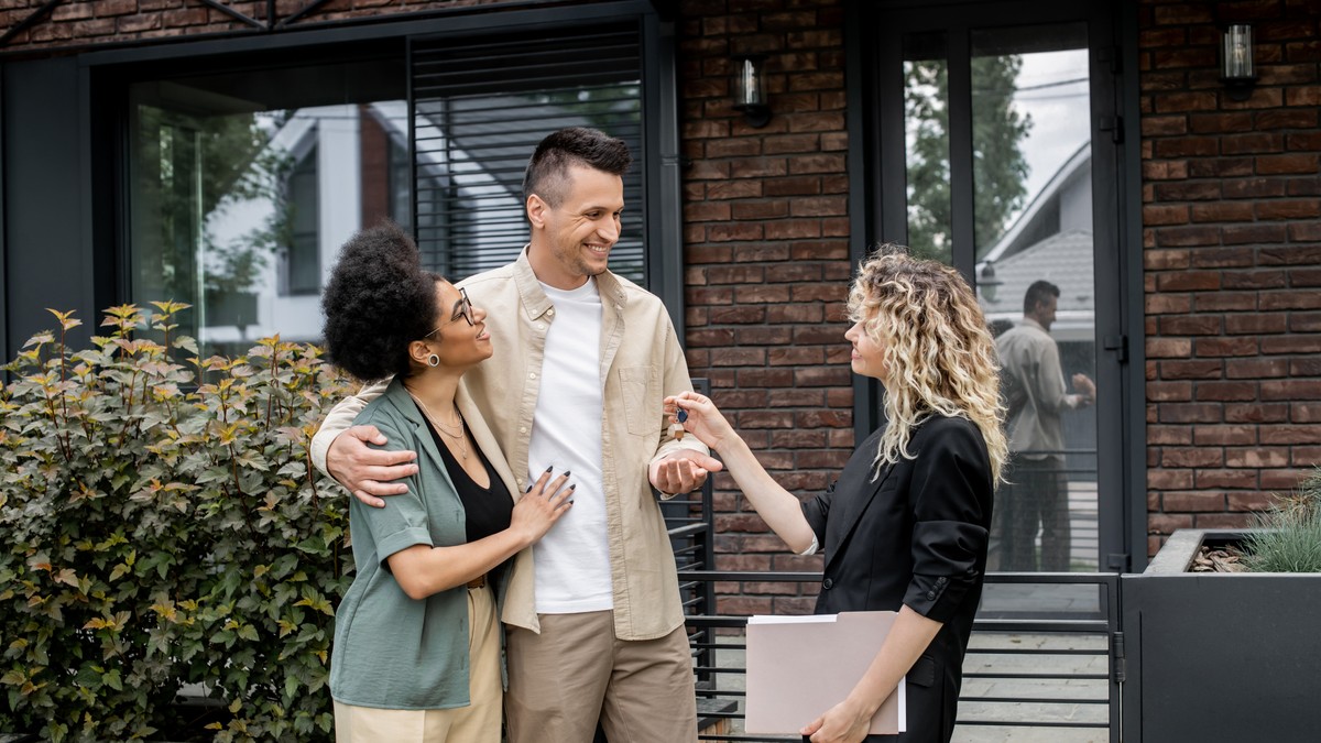 Cuplu fericit, barbat si femeie cumpara o casa. Agenta imobiliara le inmaneaza cheile casei