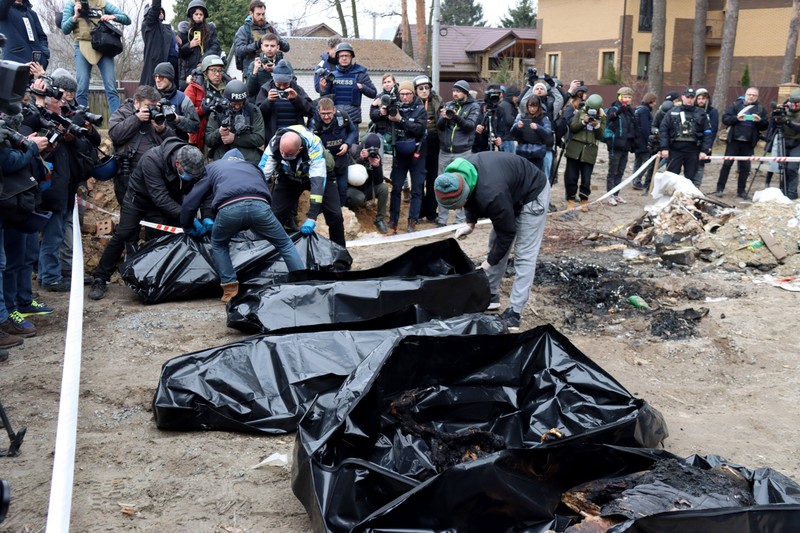 Trupurile neînsuflețite și arse ale celor care au murit în Bucha sunt puse în saci, pe 5 aprilie 2022, după ce localitatea a fost recucerită de forțele ucrainene. Foto: Profimedia.