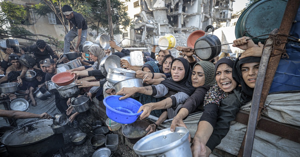 Imagine cu mai multe femei din Fâșia Gaza care țin în mâini oale și recipiente în care așteaptă să primească mâncare