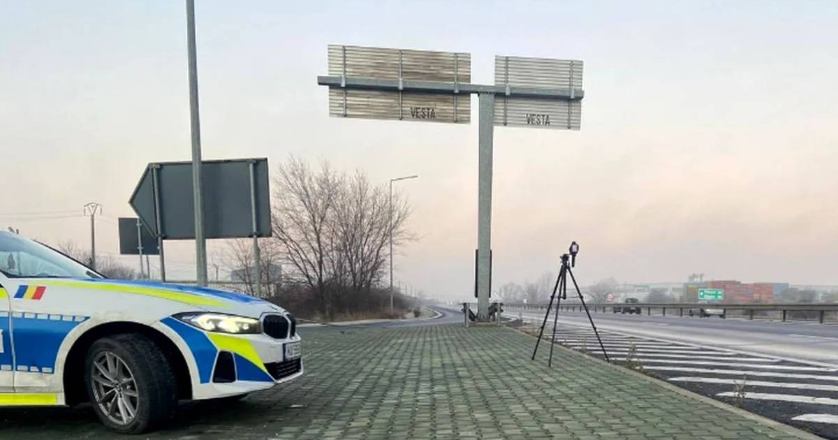 sistem radar pe trepied langa o masina de politie, in partea de sus sunt doua indicatoare rutiere de directie