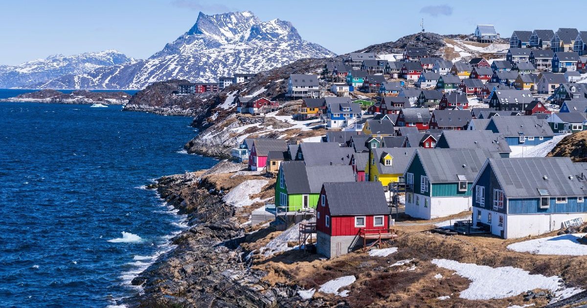 Vedere pitorească a caselor colorate cuibărite de-a lungul coastei orașului Nuuk, Groenlanda, cu muntele Sermitsiaq în fundal.