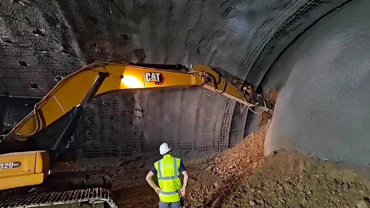 Un muncitor urmărește cum o galerie a unui tunel este străpunsă de un utilaj