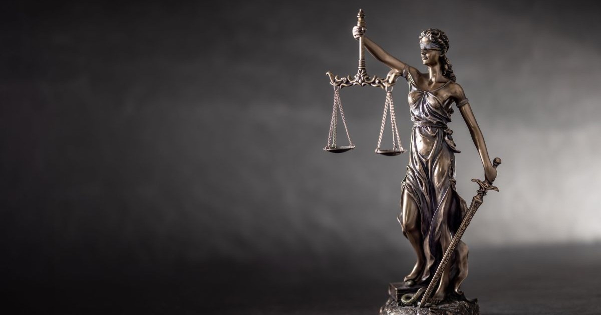 Imagine creativă cu o statuetă care arată justiția, o femeie legată la ochi și care ține o balanță într-o mână și o sabie în cealaltă
