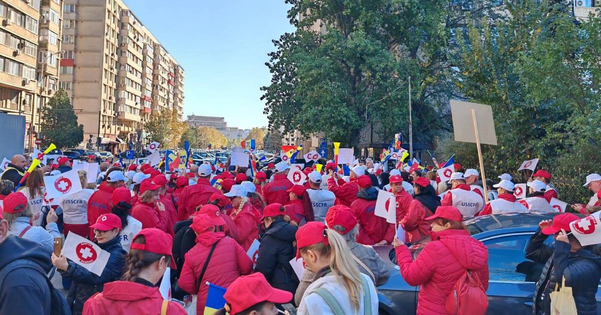 Membrii Sanitas în timpul unui protest în 2023, oamenii poartă jachete roșii și au adus cu ei pancarte