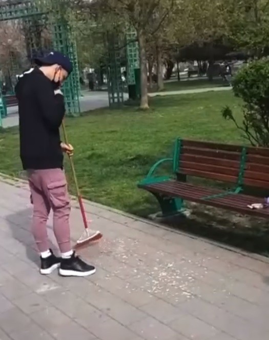 Un tânăr zâmbitor mătură o grămadă de coji făcută în mijlocul parcului Sebastian din Rahova