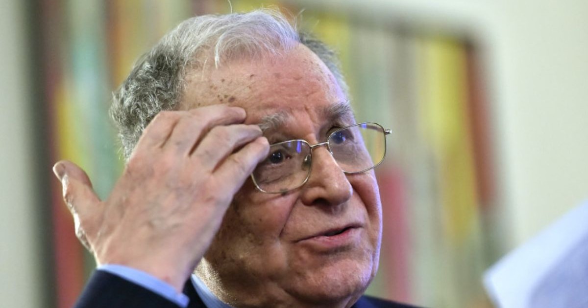 Ion Iliescu, în prim plan, în timp ce poartă ochelari și își ține o mână pe frunte