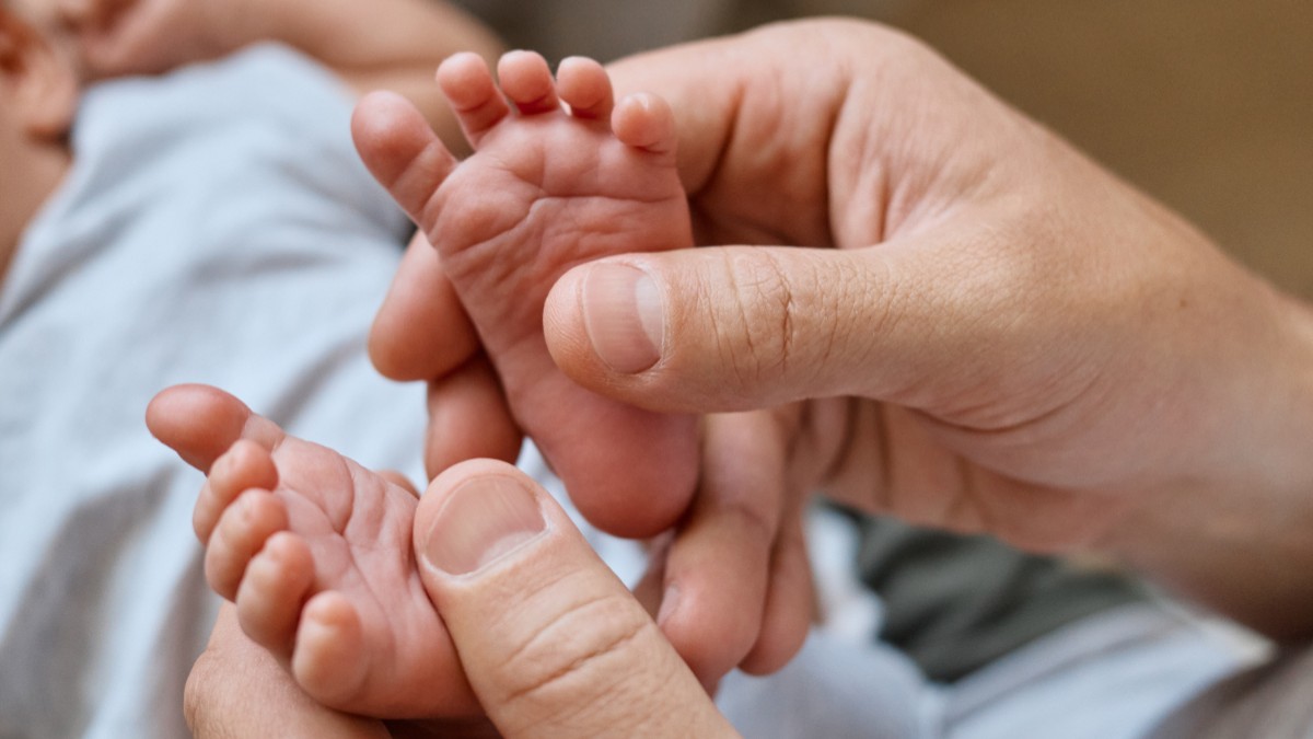 Un adult care ține tălpile unui bebeluș