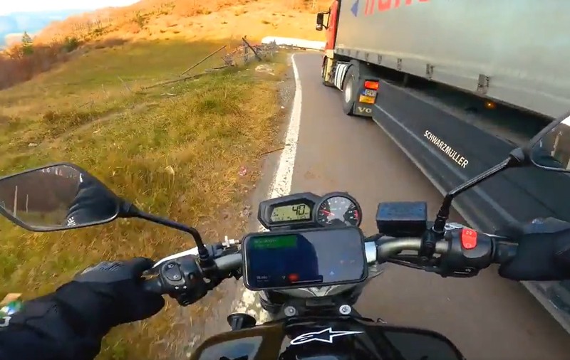 Motociclist aruncat pe câmp de un camionagiu, pe o șosea din România. Amândoi erau peste linia continuă, în curbă | VIDEO
