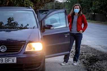 Mihaela aşteaptă elevii lângă maşina asociaţiei
