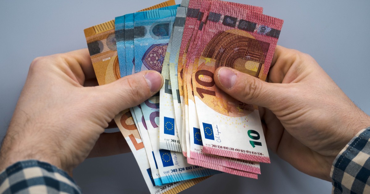 Un bărbat care ține bancnote de euro în mâini