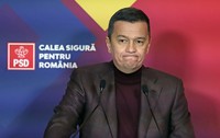 Sorin Grindeanu, îmbrăcat într-o maletă vișinie și un sacou maro cu model de caroruri gri, făcând o grimasă, cu buzele strânse și încovoiate în jos, și ochii ațintiți spre stânga
