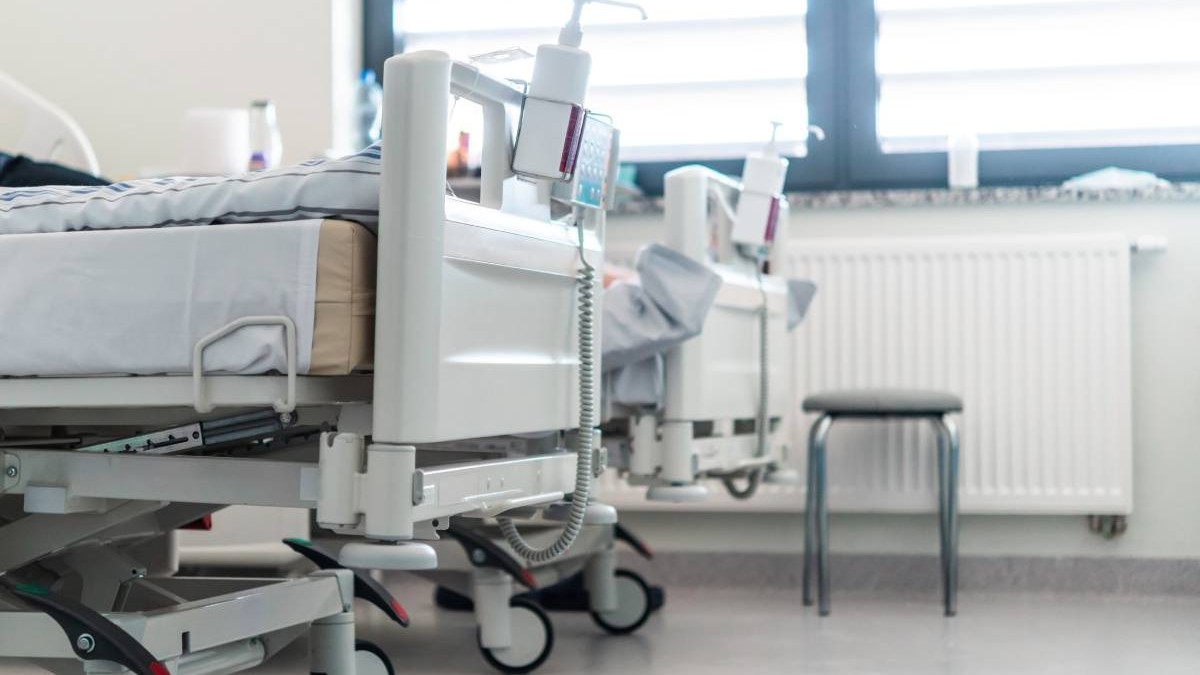 Două paturi de spital într-un salon ATI, așternuturile puse pe paturi sunt albe, fiecare pat este dotat cu dezinfectant